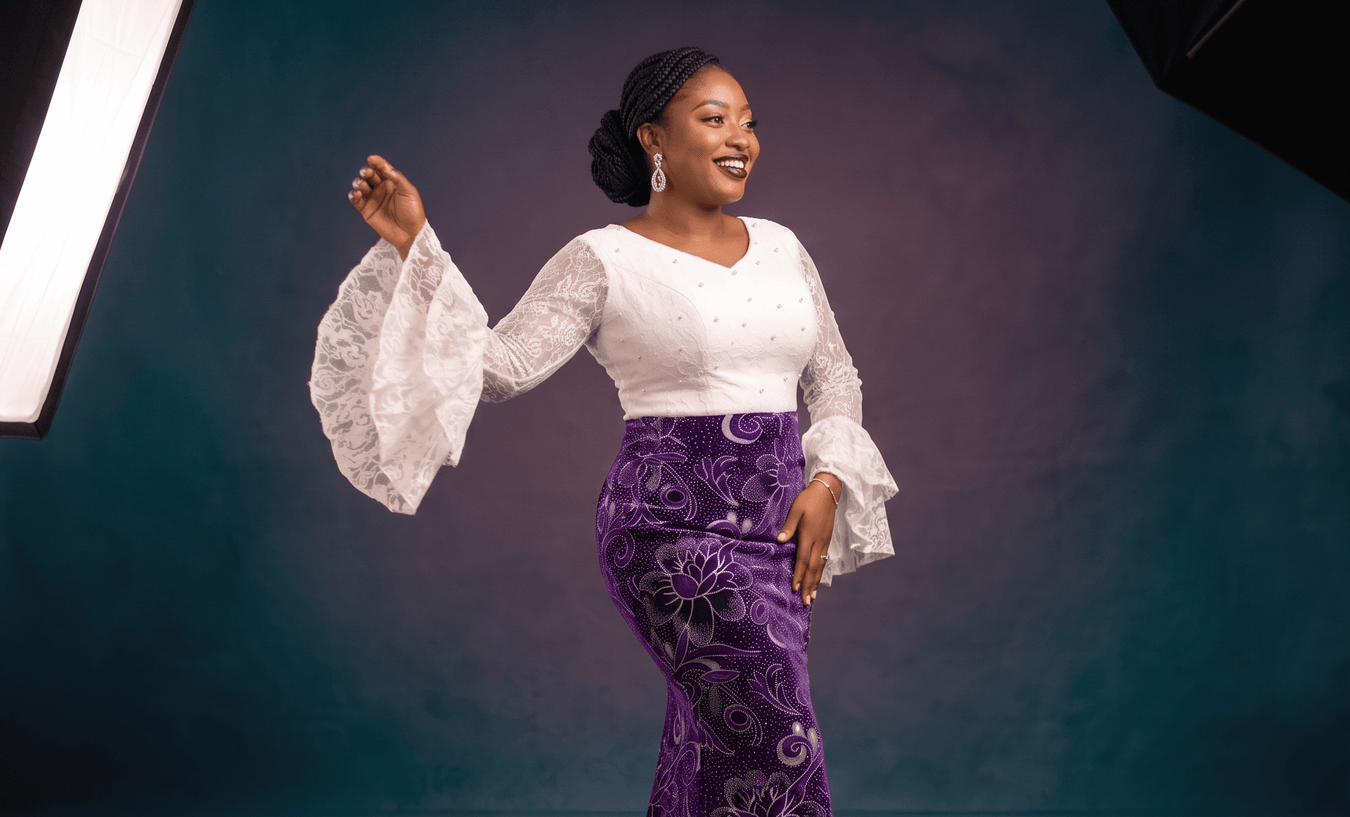 Bespoke two-piece gown featuring a hand-beaded white lace bodice with dramatic bell sleeves, seamlessly paired with a custom-tailored, floor-length purple velvet skirt adorned with silver floral motifs — Afrowear.Africa